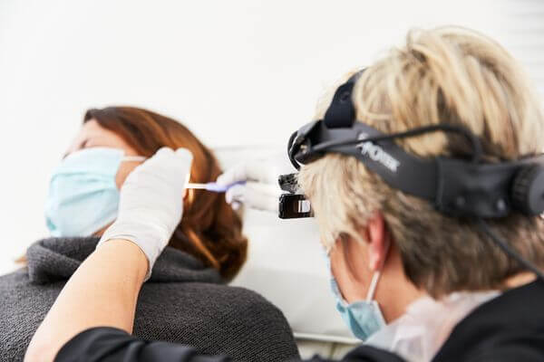 A patient in a reclined position receiving a microsuction ear wax removal procedure